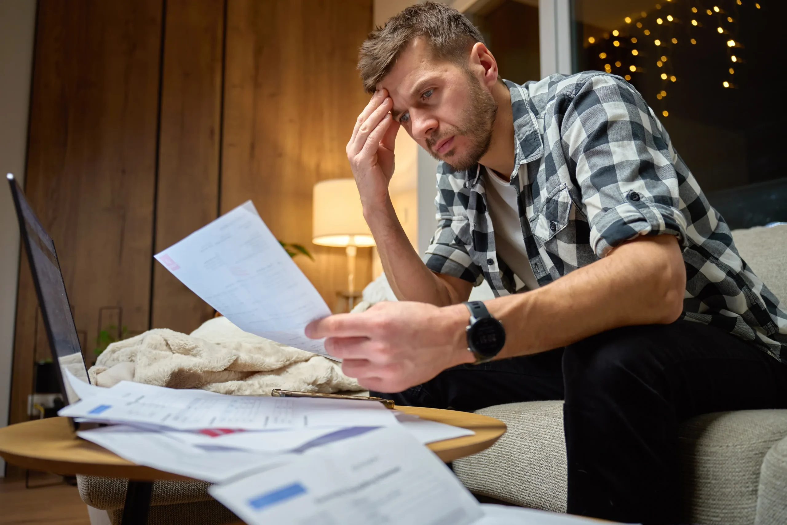 Small business owner sitting at his desk alone while reviewing paperwork and thinking about selling his business