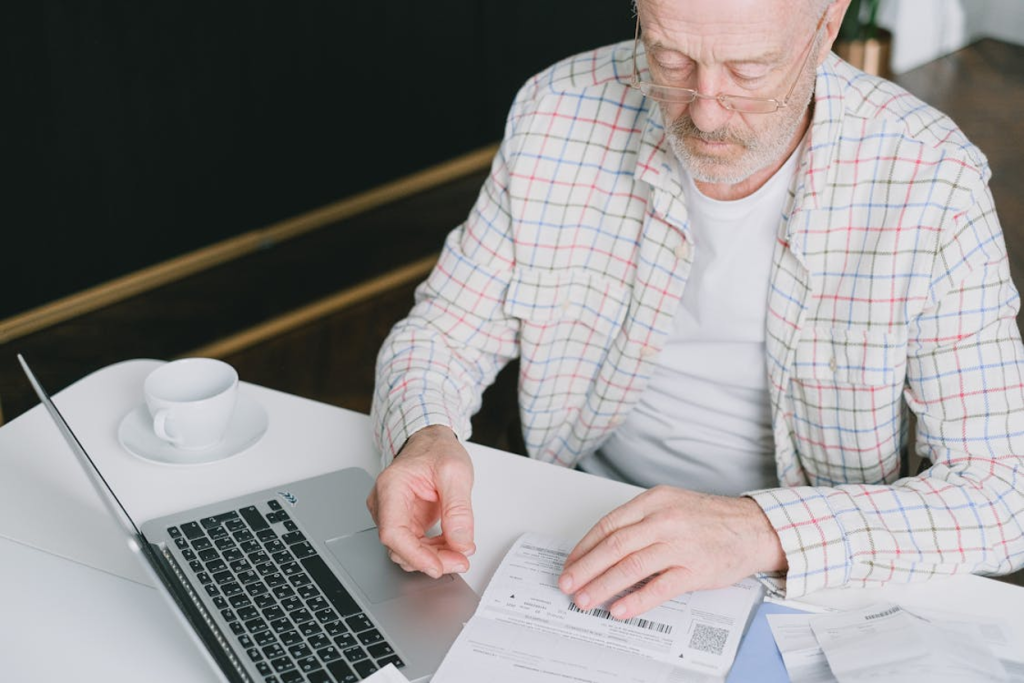 HVAC business owner reviewing sale paperwork at a desk with a laptop and coffee