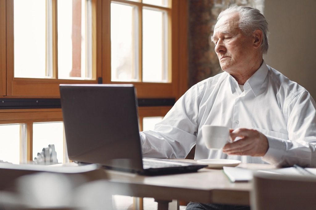 Older business owner working at a laptop with coffee and papers on the table