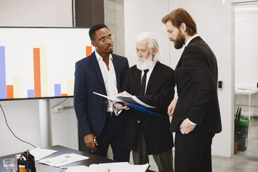 Senior business owner going over a printed financial report with two advisors