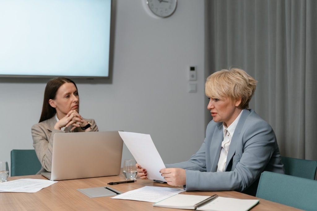 Two colleagues in a boardroom reviewing an Adjusted EBITDA statement
