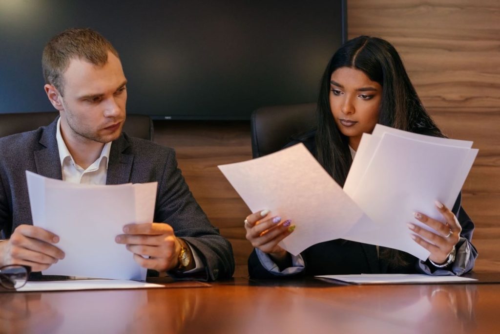 Two people reviewing separate documents at a boardroom table