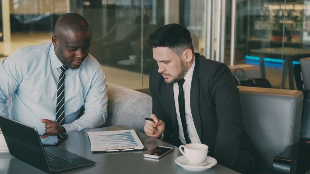 Two professionals reviewing a financial performance chart and laptop during a meeting