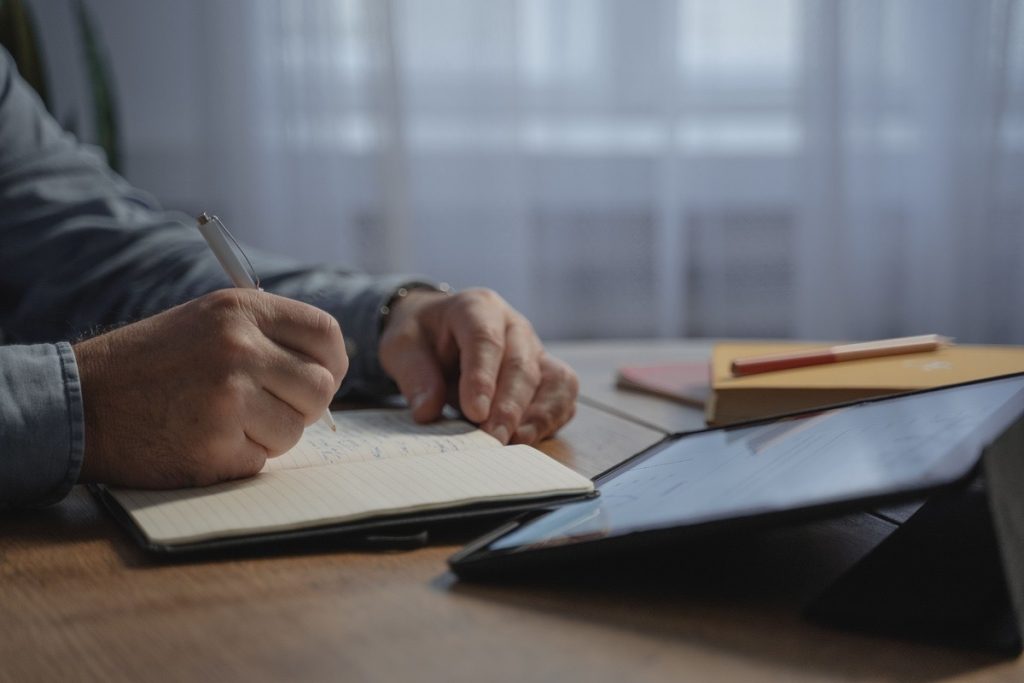 Business owner writing notes while weighing the pros and cons of an earnout