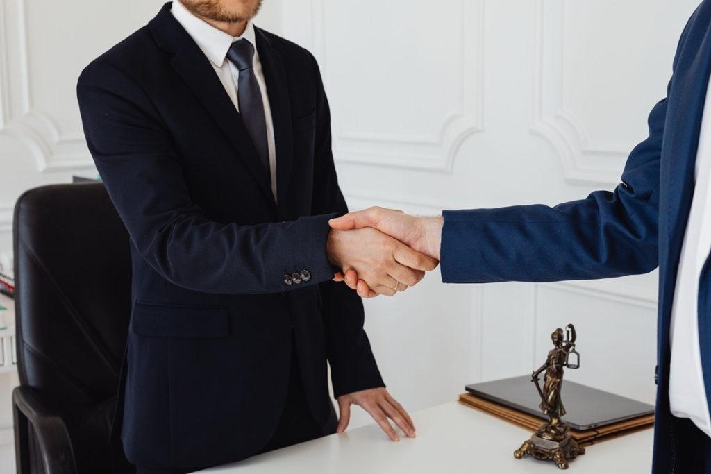 Seller and attorney shaking hands after settling legal fees for a business sale