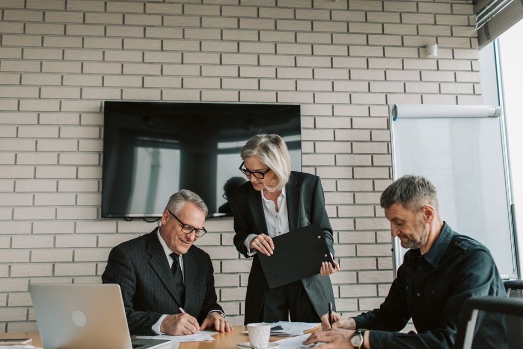 Three colleagues working through paperwork together in a meeting room