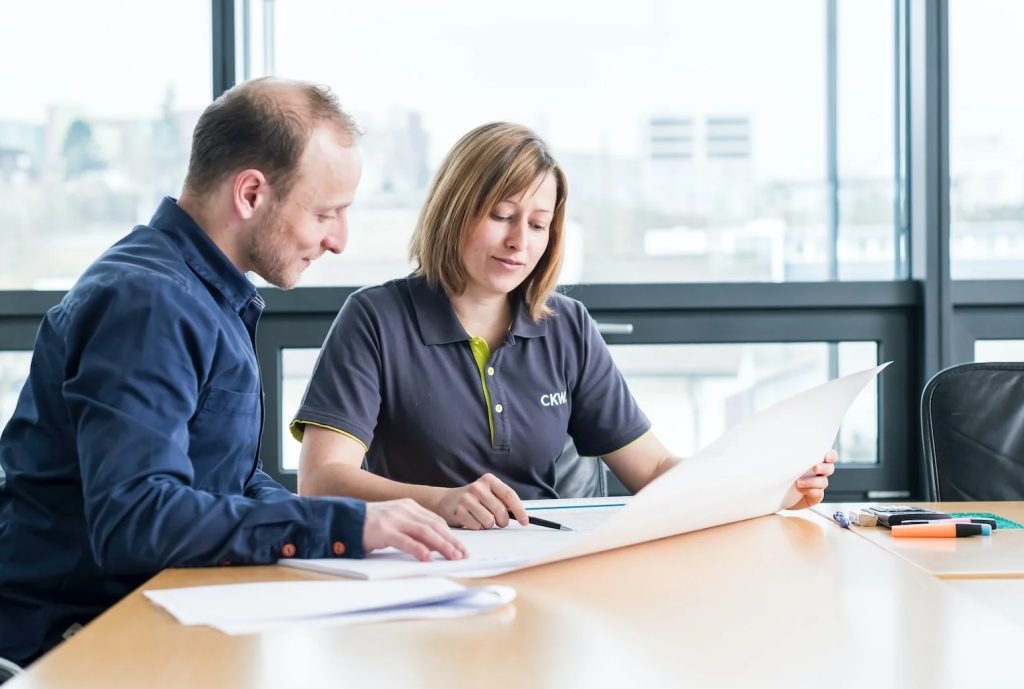 Two colleagues reviewing documents together at a desk in a bright modern office