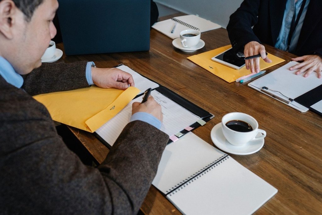 Two men taking notes across a table while reviewing tax obligations on a business sale