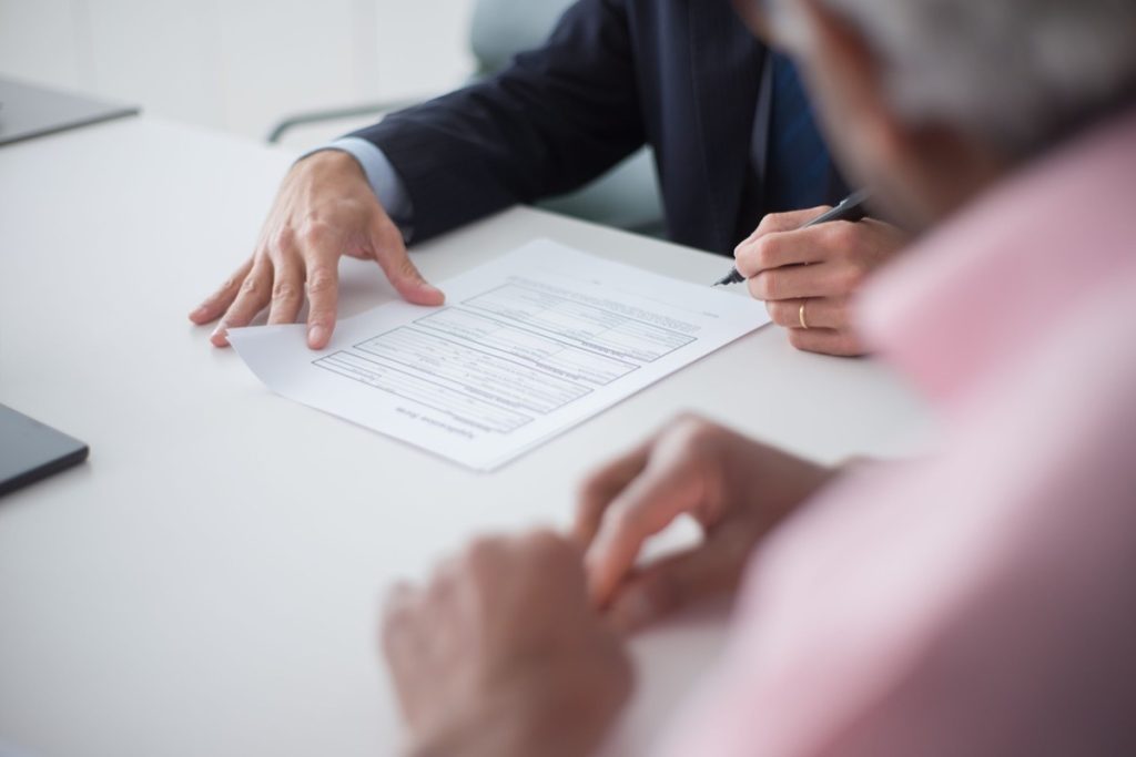 Two people across a desk reviewing a document before one of them signs.