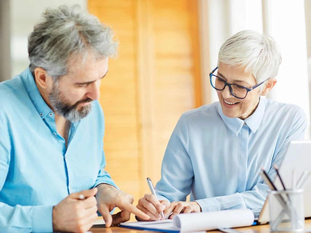 Two professionals reviewing and signing paperwork together at a desk