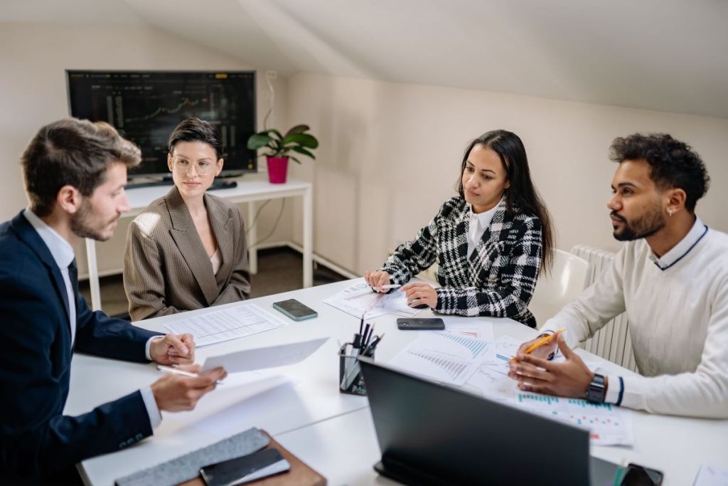 A team of professionals analyzing financial charts and valuation data in a meeting room.