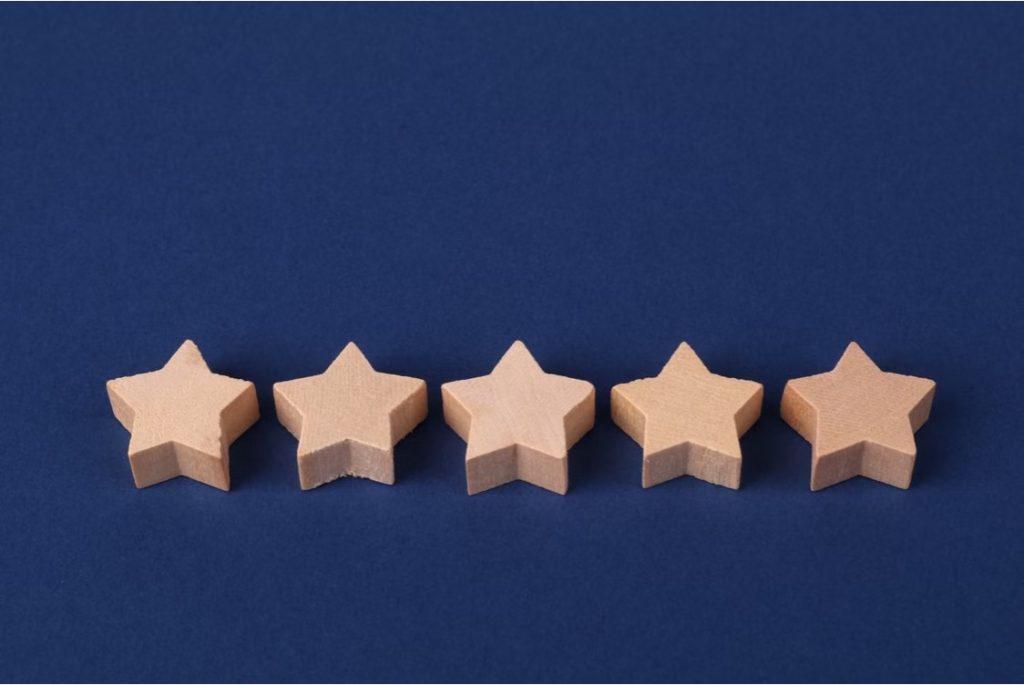 Five wooden stars on a blue background representing a rating system or evaluation concept