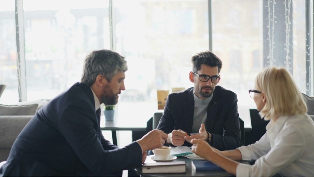 Three professionals discussing how quality of earnings findings affect business valuation