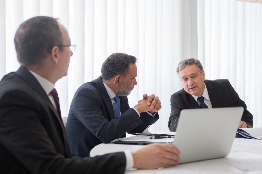 Three professionals negotiating seller financing deal terms at a conference table