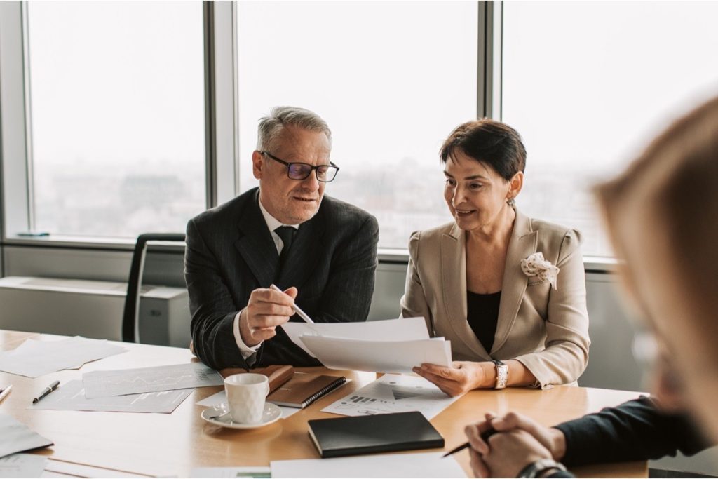 Two professionals reviewing financial documents during a quality of earnings diligence meeting.