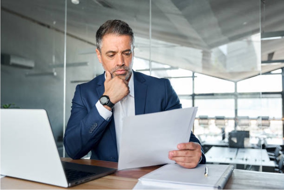 Business owner studying a purchase agreement at his desk, checking how working capital affects the sale price.