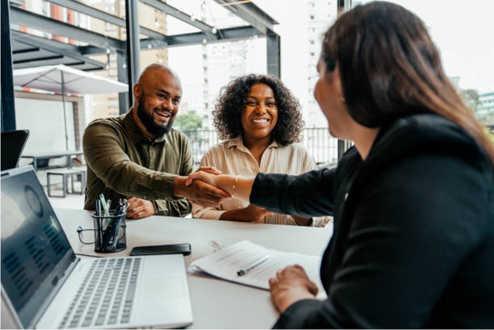 Business owners shaking hands with a buyer over a signed sale agreement that includes non-compete terms.