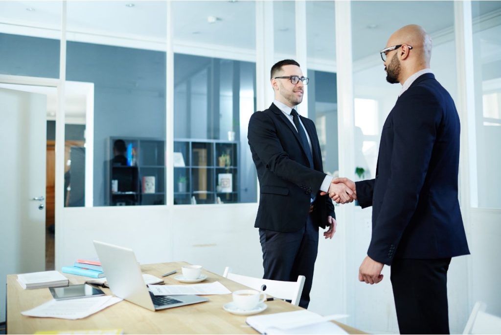Two business professionals shaking hands in a modern office